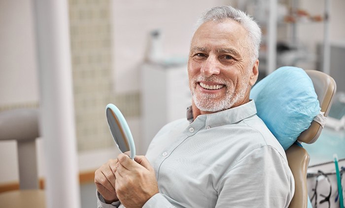 A happy older man smiling while sitting in a dental chair