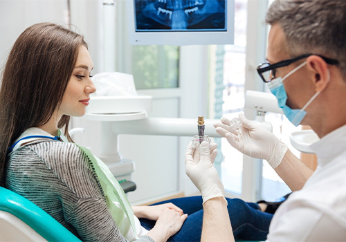 A dentist showing a dental implant model to his patient