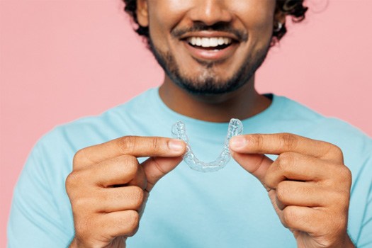 A man holding an Invisalign aligner near River Oaks